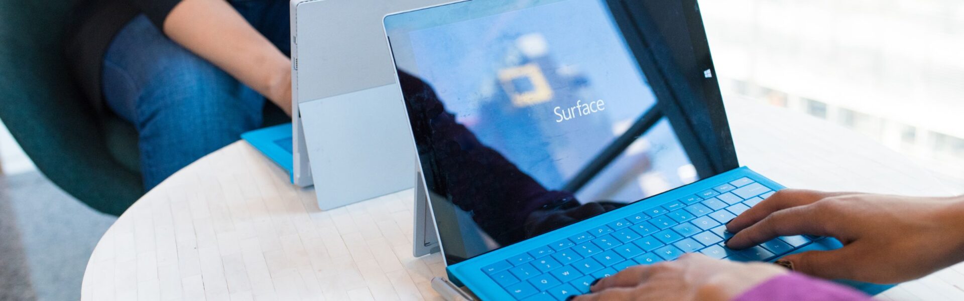 Osoba korzystająca z tabletu Microsoft Surface z podłączoną klawiaturą podczas pracy przy biurku, na ekranie widoczny system Windows, co nawiązuje do artykułu o przeglądarce Samsung Internet na Windows i jej działaniu na urządzeniach desktopowych – więcej informacji na przyspieszkomputer.pl